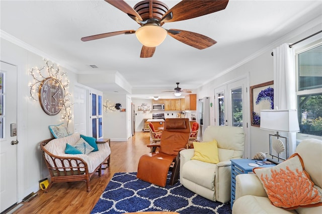 living room with ornamental molding, french doors, a wealth of natural light, and light hardwood / wood-style flooring