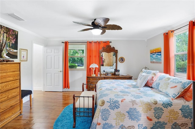 bedroom featuring ceiling fan, ornamental molding, light hardwood / wood-style flooring, and multiple windows