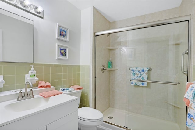 bathroom featuring walk in shower, vanity, tile walls, and toilet