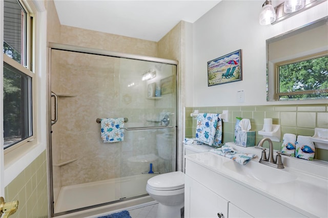 bathroom featuring vanity, a shower with shower door, tile walls, and toilet