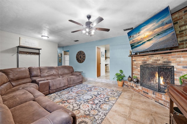 living room featuring ceiling fan, a fireplace, and a textured ceiling