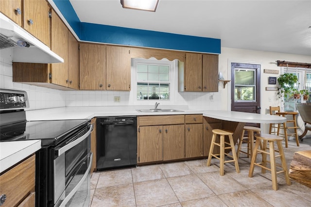 kitchen with sink, a breakfast bar area, dishwasher, range with two ovens, and backsplash