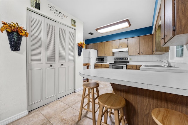 kitchen featuring sink, a kitchen breakfast bar, decorative backsplash, kitchen peninsula, and stainless steel appliances