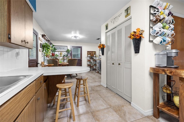 kitchen with tasteful backsplash, a kitchen bar, kitchen peninsula, and light tile patterned floors