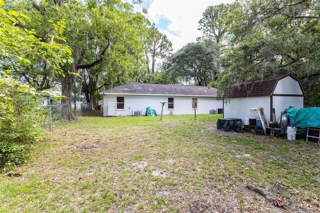 rear view of property with a yard and a storage unit