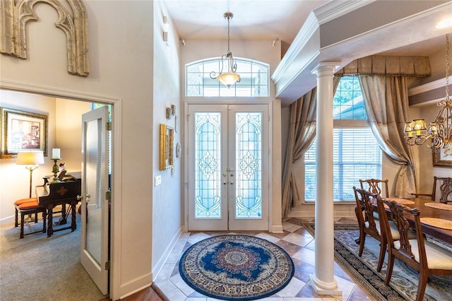 foyer entrance featuring decorative columns, ornamental molding, and french doors