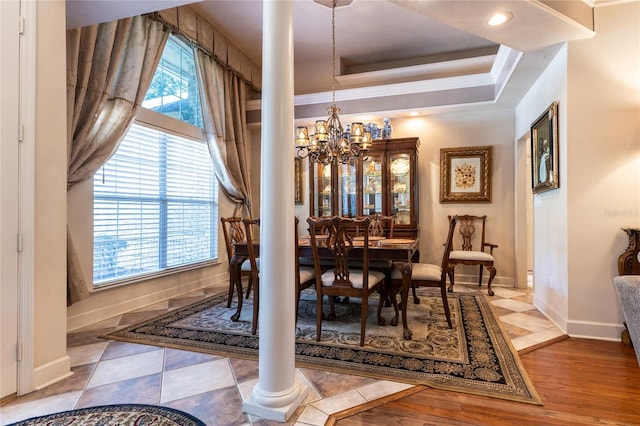 dining space with ornate columns, an inviting chandelier, crown molding, a tray ceiling, and light tile patterned floors