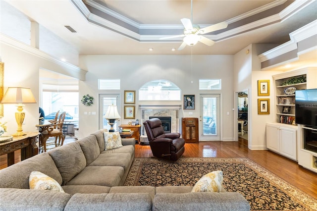 living room featuring a raised ceiling, a wealth of natural light, and crown molding