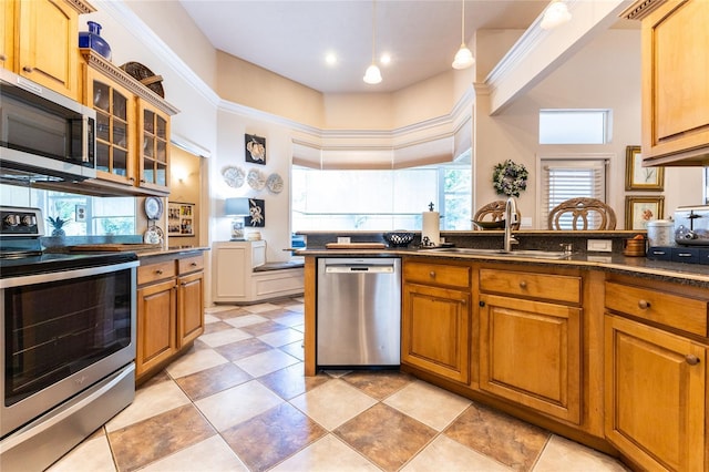 kitchen with decorative light fixtures, sink, appliances with stainless steel finishes, and a high ceiling