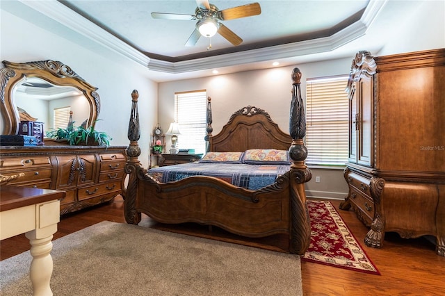 bedroom featuring a tray ceiling, ceiling fan, ornamental molding, and dark hardwood / wood-style floors