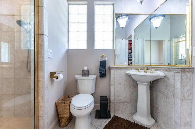 bathroom featuring tile patterned floors, a tile shower, and toilet