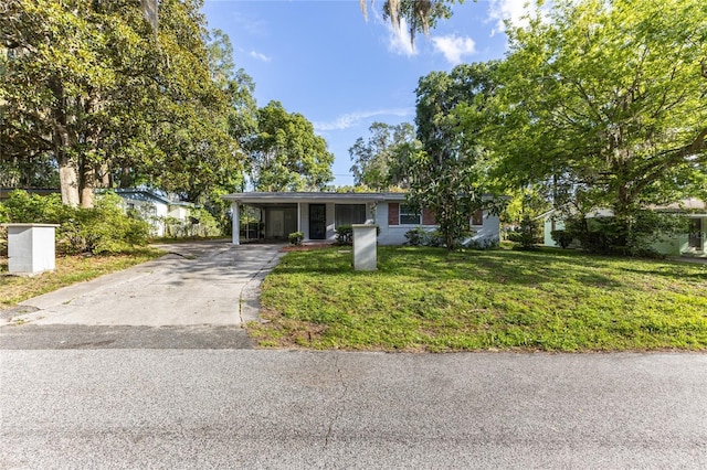 ranch-style house featuring concrete driveway, a carport, and a front yard