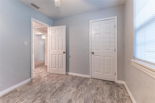 unfurnished bedroom with visible vents, a textured wall, ceiling fan, wood finished floors, and baseboards