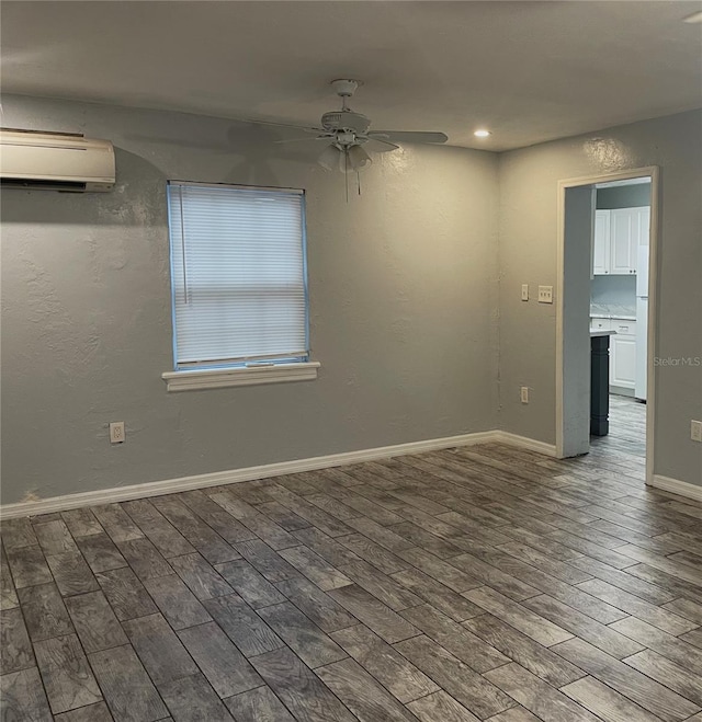 spare room featuring ceiling fan, an AC wall unit, wood finished floors, and baseboards