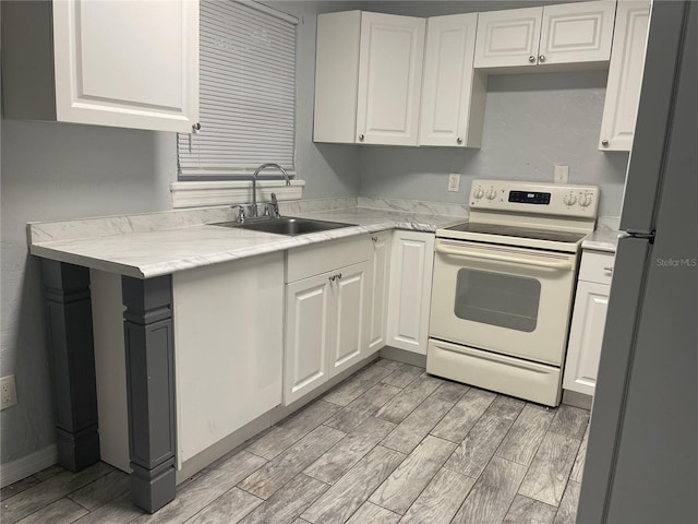 kitchen featuring white cabinets, electric stove, freestanding refrigerator, wood finish floors, and a sink