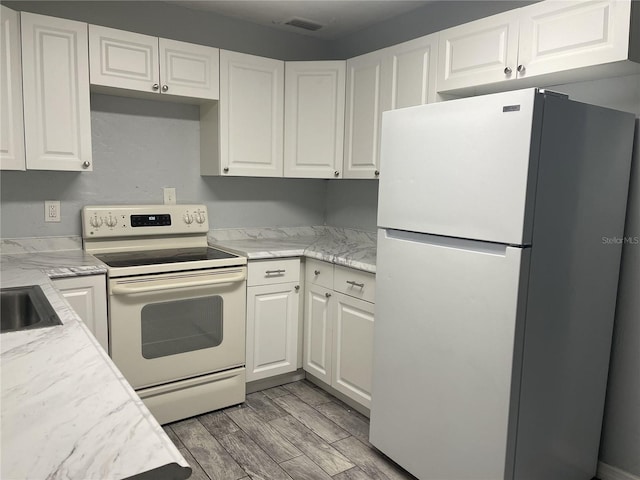 kitchen with white appliances, light wood-style flooring, and white cabinetry