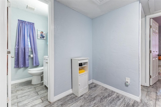 bathroom with wood tiled floor, baseboards, and toilet