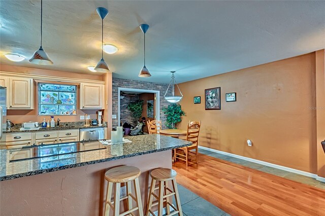 kitchen featuring dishwasher, hanging light fixtures, gas cooktop, dark stone counters, and light hardwood / wood-style floors