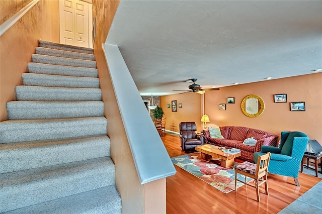 stairs featuring wood-type flooring and ceiling fan