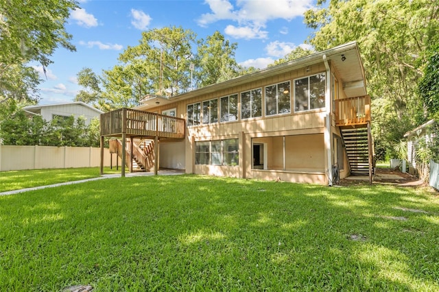 rear view of house featuring a sunroom, a deck, and a lawn