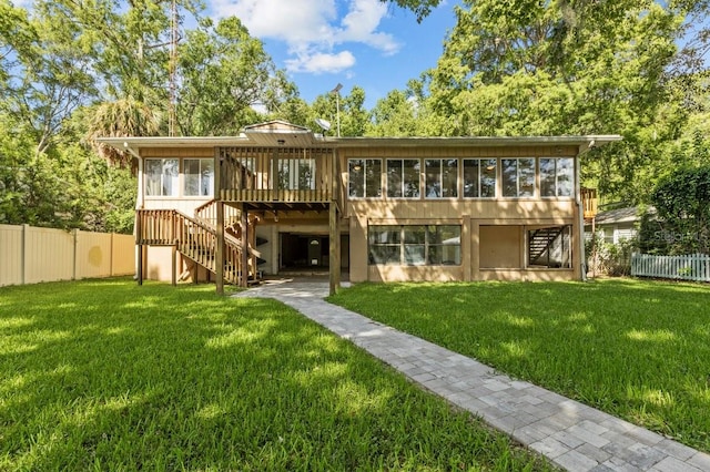 rear view of house featuring a sunroom and a yard