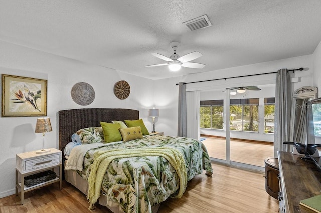 bedroom with access to outside, light hardwood / wood-style floors, a textured ceiling, and ceiling fan