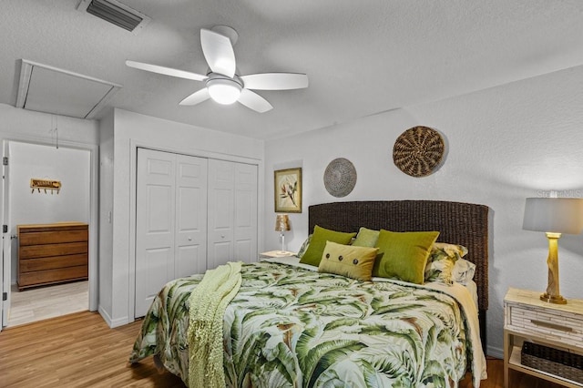 bedroom with light hardwood / wood-style floors, a textured ceiling, a closet, and ceiling fan