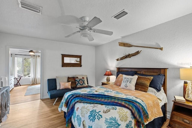 bedroom with a textured ceiling, ceiling fan, and hardwood / wood-style floors