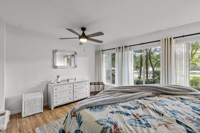 bedroom with ceiling fan, light hardwood / wood-style flooring, and a textured ceiling