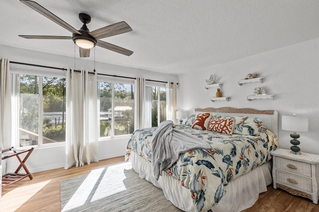 bedroom featuring a textured ceiling, ceiling fan, and light hardwood / wood-style flooring