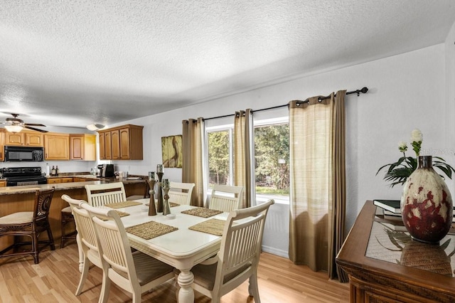 dining room with a textured ceiling, ceiling fan, and light wood-type flooring