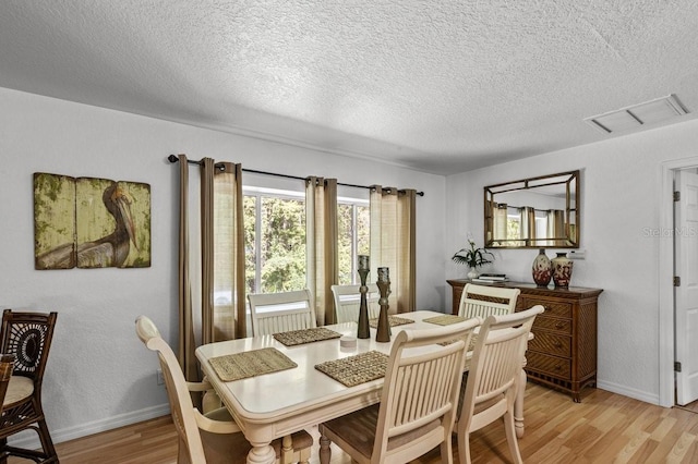 dining room with a textured ceiling and light wood-type flooring