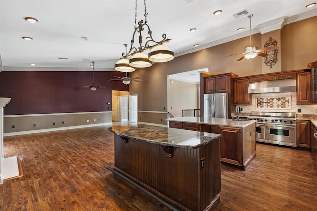 kitchen with stone counters, a breakfast bar area, a center island, stainless steel appliances, and wall chimney exhaust hood