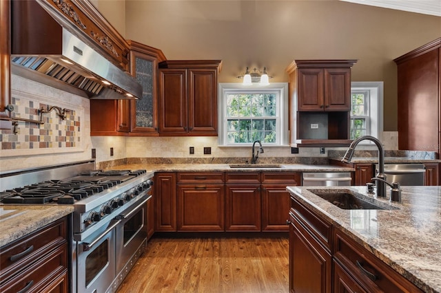 kitchen featuring wall chimney exhaust hood, stainless steel appliances, sink, and light wood-type flooring