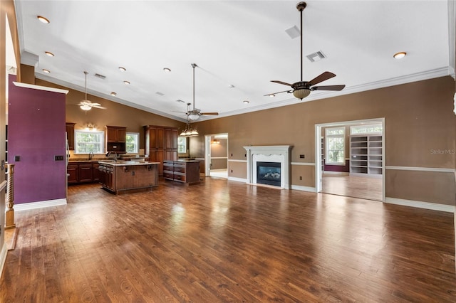 unfurnished living room with lofted ceiling, sink, crown molding, dark wood-type flooring, and ceiling fan