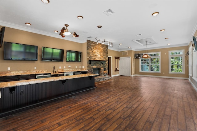 kitchen featuring a breakfast bar, pendant lighting, a fireplace, crown molding, and dark wood-type flooring