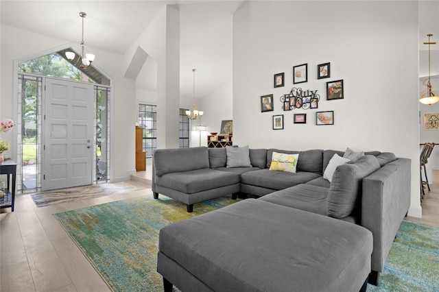 living room featuring light hardwood / wood-style floors, high vaulted ceiling, and an inviting chandelier