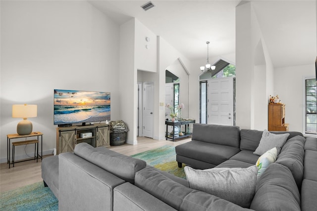 living room with a chandelier, high vaulted ceiling, and light hardwood / wood-style flooring