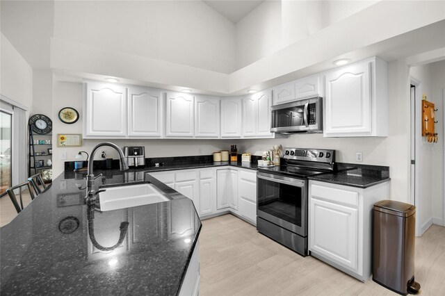 kitchen with white cabinets, sink, appliances with stainless steel finishes, and dark stone counters