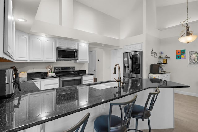 kitchen featuring kitchen peninsula, white cabinetry, decorative light fixtures, and appliances with stainless steel finishes