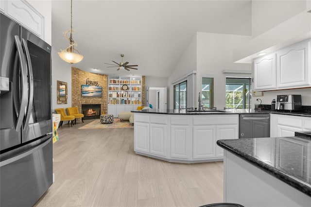 kitchen with pendant lighting, white cabinets, sink, a brick fireplace, and stainless steel appliances