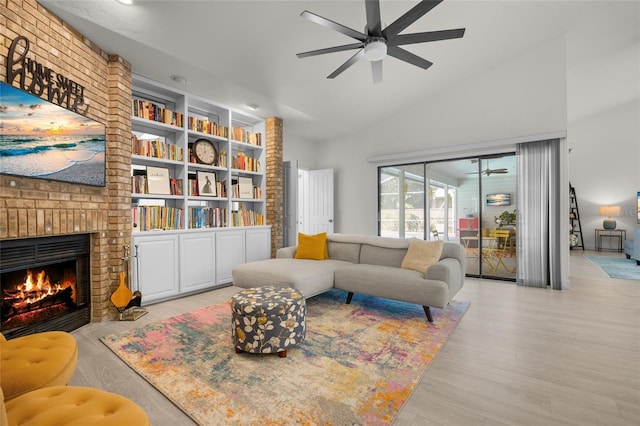 living room featuring lofted ceiling, light hardwood / wood-style flooring, a brick fireplace, ceiling fan, and built in features