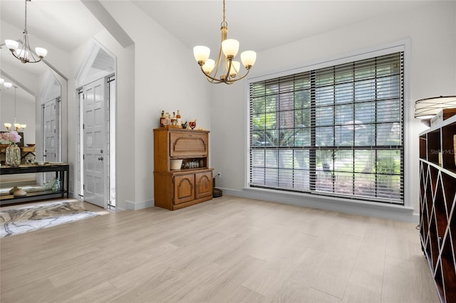 interior space with light hardwood / wood-style floors, lofted ceiling, and a notable chandelier