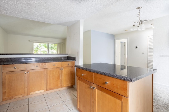 kitchen featuring dark stone counters, pendant lighting, a textured ceiling, and light tile patterned flooring