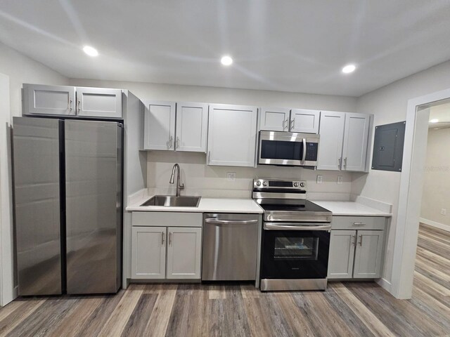 kitchen featuring appliances with stainless steel finishes, electric panel, hardwood / wood-style flooring, and sink