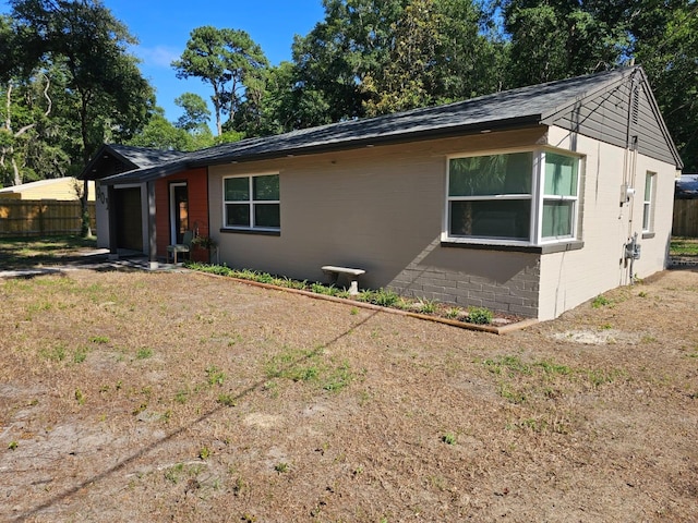 view of front of property featuring brick siding, concrete block siding, an attached garage, and fence