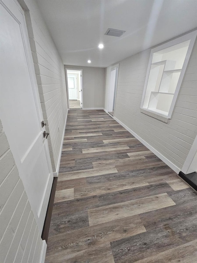 hall with dark wood-type flooring and brick wall