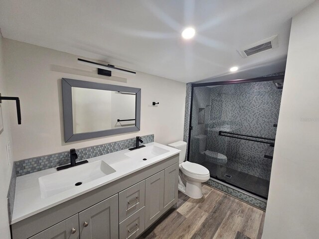 bathroom with tasteful backsplash, an enclosed shower, vanity, wood-type flooring, and toilet