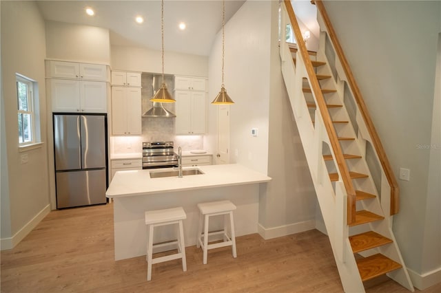 kitchen featuring wall chimney exhaust hood, sink, white cabinetry, stainless steel appliances, and backsplash