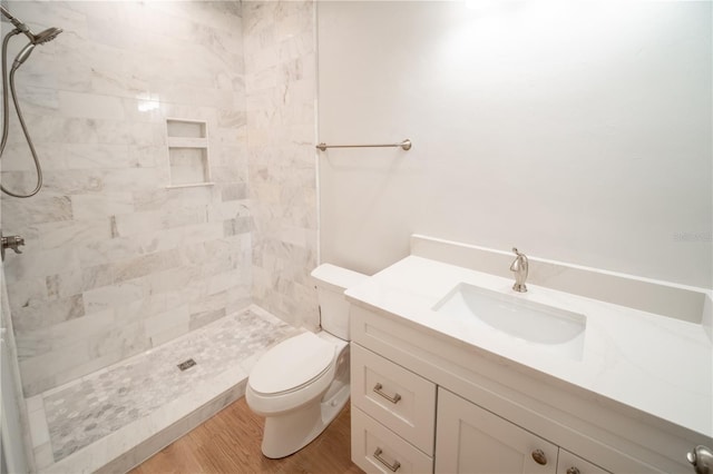 bathroom with vanity, wood-type flooring, toilet, and tiled shower